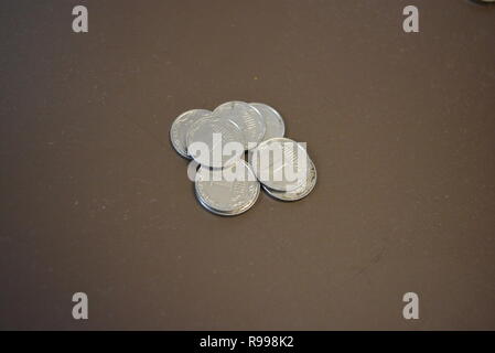 Metallkleiniggeld auf braunem Hintergrund, ukrainische Griwna und einen Penny, Bankzahlung, Schätze und Barzahlungen, Sparguthaben in der Bank. Stockfoto