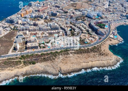 Meer Felsen, bunte Häuser und Straßen der Stadt Qawra in St. Paul's Bay Area in der nördlichen Region, Malta. Beliebter Ferienort zwischen Bugibba und Salina. Luftaufnahme. Malta Insel von oben Stockfoto