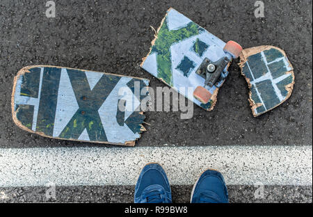 Gebrochene skateboard auf dunklen Asphalt Straße. Junge mit Sneakers trat auf Skateboard. Street Line. Stockfoto