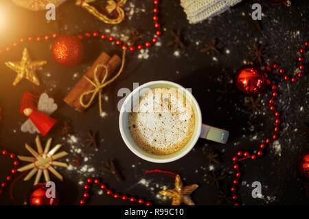 Flach von Kaffee auf einem schwarzen Hintergrund mit roten Spielzeug, Kugeln und Perlen, Ansicht von oben. Neues Jahr, Weihnachten, Urlaub, Feier, winter Konzepte. Stockfoto