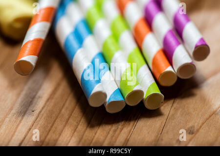 Mehrfarbige Trinkhalme auf hölzernen Tisch gelegt. Lebendige Farben trinken Strohhalme aus Papier. Nahaufnahme Makroaufnahme. Stockfoto