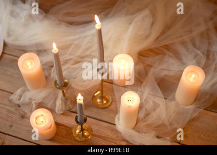 Wellness, Gesundheit, Beauty und Wellness Konzept mit Rosenblüten um brennende Kerzen verstreut auf einem Holzboden in einem hohen Winkel anzeigen Stockfoto