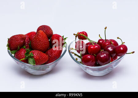 Ein Glas Schüssel voll von Kirsche und eine Schale voller Erdbeeren auf den Tisch Stockfoto