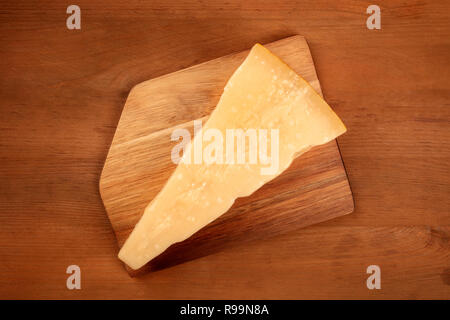 Ein Stück alter Parmesankäse, Schuß von der Oberseite in einem dunklen Holzmöbeln im Landhausstil Hintergrund mit Kopie Raum Stockfoto