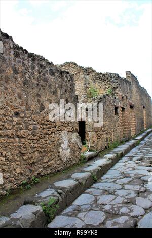 Ein Blick entlang der Überreste einer Straße in der antiken Stadt Pompeji, Italien, das war durch den Ausbruch des Vulkans Vesuv im Jahr 79 N.CHR. zerstört. Stockfoto