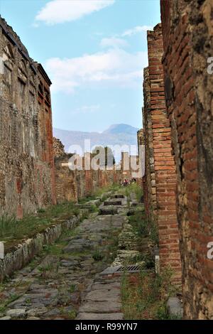 Pompeji, Italien - 23. Oktober 2018: ein Blick auf eine zerstörte Straße in der antiken Stadt Pompeji, mit dem Vesuv Vulkan im Hintergrund. Stockfoto