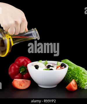 Salat mit Olivenöl Ausgießen aus der Flasche. Stockfoto