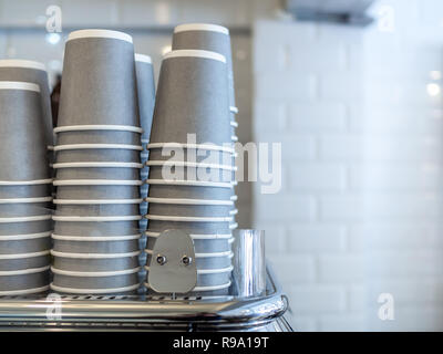 Stapel von grauem Papier Becher, heißen Kaffee Tassen, Getränkebecher auf Kaffee Maschine im Cafe auf der weißen Wand Hintergrund mit kopieren. Stockfoto