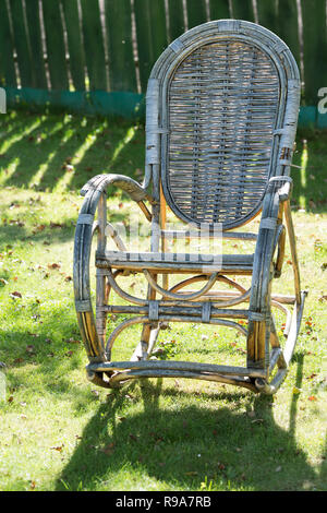 Alte rattan Schaukelstuhl im Garten auf der Wiese Stockfoto