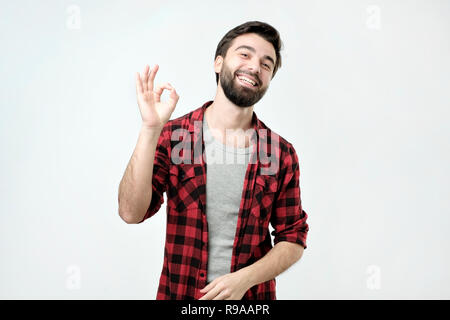 Glückliche junge Mann im Hemd Gestik OK Zeichen und lächelnd Stockfoto