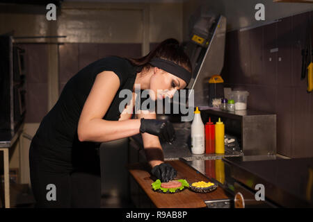 Frau Koch bereitet köstliche frische Burger in der Küche im Restaurant Stockfoto