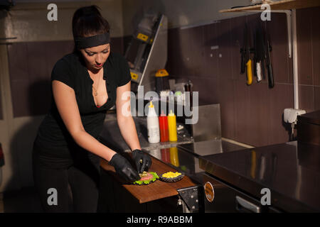 Frau Koch bereitet köstliche frische Burger in der Küche im Restaurant Stockfoto