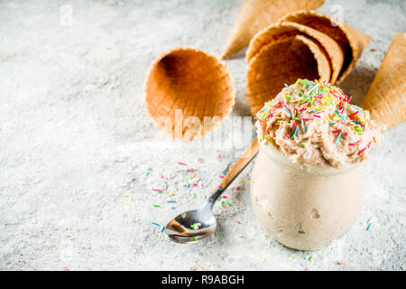 Essbarer Rohstoff Plätzchenteig, süße moderne Dessert, mit Waffel Eistüten auf grauem Stein, kopieren Raum Stockfoto