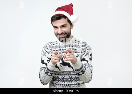 Aufgeregt, bärtigen Mann in rot weihnachten cap Pointing Finger an Kamera Stockfoto