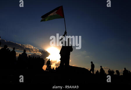 Gaza und die Palästinensischen Gebiete. 21. Dez 2018. Palästina - Silhouette eines Palästinensischen Mann gesehen, eine Flagge während der Proteste auf der Trennungsmauer zwischen Gaza und Israel. Credit: Yousef Masoud/SOPA Images/ZUMA Draht/Alamy leben Nachrichten Stockfoto