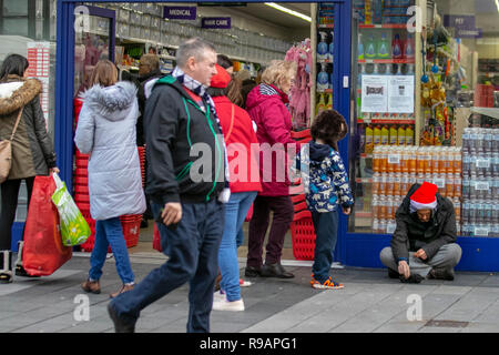 Southport Town Center, Merseyside, Großbritannien. Dezember 2018. Menschen, die an obdachlosen, raggregten Männern vorbeiziehen und Weihnachten Weihnachtsmann mit rotem Hut tragen. Kredit: MediaWorldImages/Alamy Live News Stockfoto