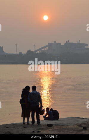 Kolkata, Indien. 22. Dezember, 2018. Menschen beobachten Sie den Sonnenuntergang über Kolkata Skyline am Tag der Wintersonnenwende in der nördlichen Hemisphäre vom AJC Bose indische Botanischer Garten angrenzenden Ghat der Fluss Hooghly in Howrah. Credit: Biswarup Ganguly/Alamy leben Nachrichten Stockfoto