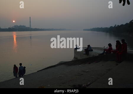 Kolkata, Indien. 22. Dezember, 2018. Menschen beobachten Sie den Sonnenuntergang über Kolkata Skyline am Tag der Wintersonnenwende in der nördlichen Hemisphäre vom AJC Bose indische Botanischer Garten angrenzenden Ghat der Fluss Hooghly in Howrah. Credit: Biswarup Ganguly/Alamy leben Nachrichten Stockfoto