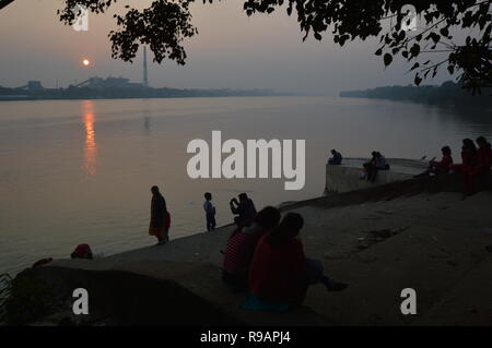 Kolkata, Indien. 22. Dezember, 2018. Menschen beobachten Sie den Sonnenuntergang über Kolkata Skyline am Tag der Wintersonnenwende in der nördlichen Hemisphäre vom AJC Bose indische Botanischer Garten angrenzenden Ghat der Fluss Hooghly in Howrah. Credit: Biswarup Ganguly/Alamy leben Nachrichten Stockfoto