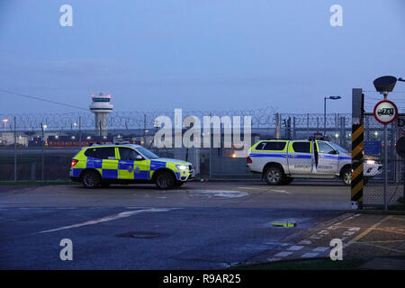 Gatwick, London, UK, 22. Dezember 2018. der Flughafen London Gatwick, GROSSBRITANNIEN - Polizei und Sicherheitsbeamte schützen Start- und Landebahn und control tower als Flughafen ist offen für Flüge am Morgen des 22. Dezember 2018, nur wenige Stunden, nachdem ein Mann und eine Frau wurden wegen des Verdachts der Drohnenangriffe, die den Flughafen mehrmals über einen Zeitraum von Tagen, wodurch Weihnachtsferien Elend und Chaos für geschätzte 150.000 Passagiere verschlossen hatte verhaftet. Credit: Andrew Stehrenberger/Alamy leben Nachrichten Stockfoto