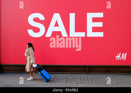 Käufer vorbei Verkauf Zeichen auf der Oxford Street, London. Stores begann früh Verkauf, vor Weihnachten, da Sie mehr Kunden zu gewinnen versuchen. Stockfoto