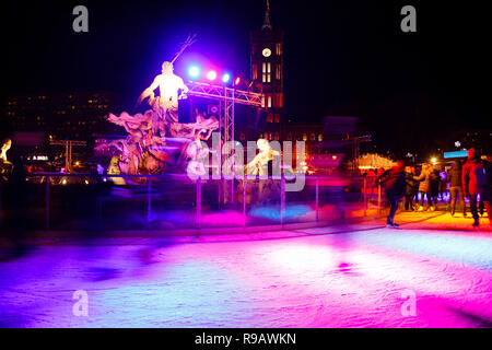 Leute Eislaufen auf der Eisbahn am Weihnachtsmarkt in Mitte, Berlin, Deutschland in der Nacht. Skater sind verschwommen in Bewegung. Rote Stadt Hall (Rotes Rathaus Stockfoto