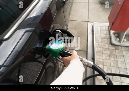 Weibliche Hand füllen Benzin in einem Auto mit Gas Pumpe Düse Stockfoto