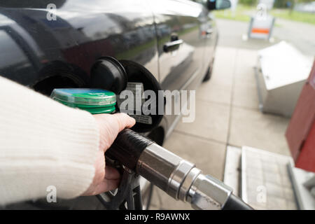 Weibliche Hand füllen Benzin in einem Auto mit Gas Pumpe Düse Stockfoto