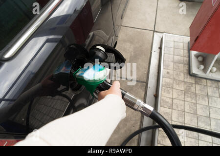 Weibliche Hand füllen Benzin in einem Auto mit Gas Pumpe Düse Stockfoto