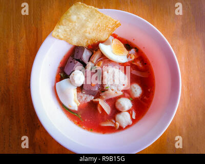 Nudeln mit Meeresfrüchten auf rote Suppe/heiß und würzig Thai Essen Nudeln mit Meeresfrüchten squid Schweinefleisch fisch Kugel und Morning glory knusprige Wan-tan Haut gekochten Ei und Por Stockfoto