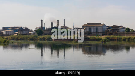 Blick über den großen Fluss Nil in Ägypten durch die ländliche Landschaft mit indutrial Zuckerrohr Fabrik verursacht Verschmutzungen Stockfoto