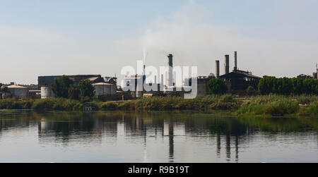 Blick über den großen Fluss Nil in Ägypten durch die ländliche Landschaft mit indutrial Zuckerrohr Fabrik verursacht Verschmutzungen Stockfoto