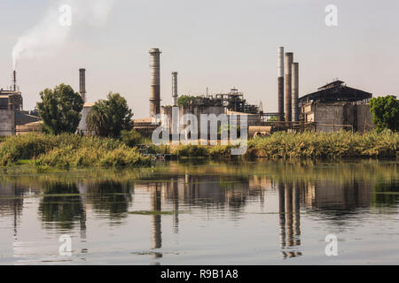 Blick über den großen Fluss Nil in Ägypten durch die ländliche Landschaft mit indutrial Zuckerrohr Fabrik verursacht Verschmutzungen Stockfoto