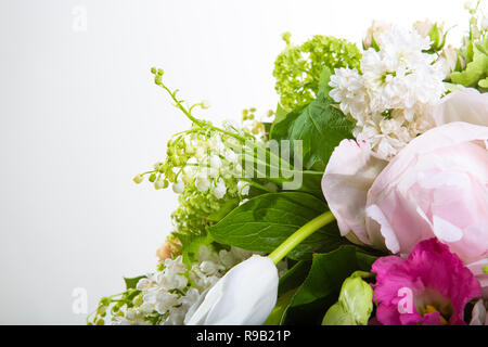 Eine große Anzahl von yety, einem großen üppigen Strauß Schneeglöckchen, Rose, Bell und Pfingstrose mit Grüns in einer grossen langen eleganten transparenten Vase auf dem Bein auf ein wh Stockfoto