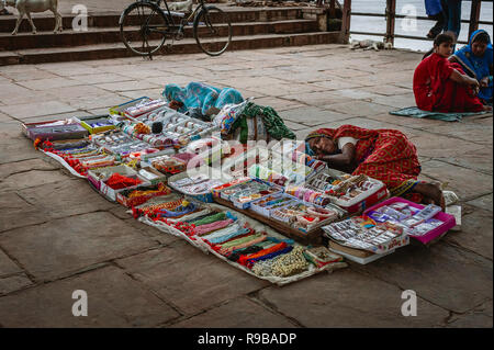 Frauen nehmen eine Siesta vom Verkauf der Schmuckstücke auf einem Gehsteig im Schatten im Freien am 14. August 2011 in Varanasi, Uttar Pradesh, Indien. Stockfoto