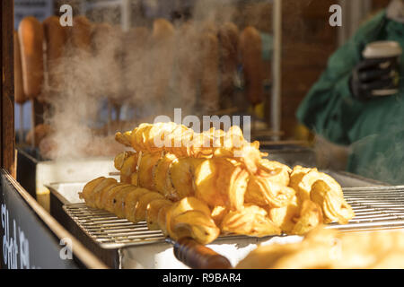 Frittierte Kartoffel Spiralen, an den Kiosk an Weihnachten Street Food Markt angezeigt. Fast food, Bratkartoffeln auf dem Stiel. Stockfoto