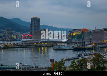 Nagasaki, Japan - 23. Oktober 2018: Nagasaki Hafen mit Fähren und cruiseboats umgeben von Bergen in der Dämmerung Stockfoto