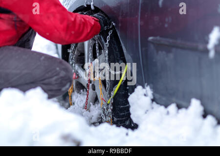 Junger Mann vorbereiten Auto im Winter Tag unterwegs. Schneeketten auf die Räder des Autos. Stockfoto