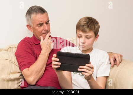 Enkel den Großvater mit Tablet, elektronisches Gerät, Social Media der modernen Technologie. Junge helfen alternden Vater mit dem iPad Tablet. Stockfoto