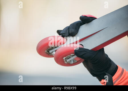 Training ein Athlet auf der Walze Skater. Biathlon Fahrt auf dem Roller Ski mit Skistöcke, im Helm. Herbst Training. Roller Sport. Der Athlet geht und hält in seiner Hand. Stockfoto