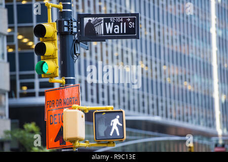 Wall Street Schild im Vordergrund und eine riesige verschwommenes Gebäude im Hintergrund in Manhattan. Stockfoto