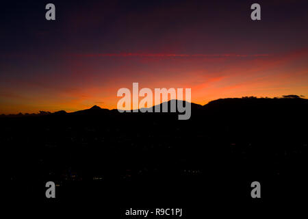 Luftaufnahme von einen spektakulären Sonnenuntergang hinter einigen schönen Bergen in Italien. Stockfoto