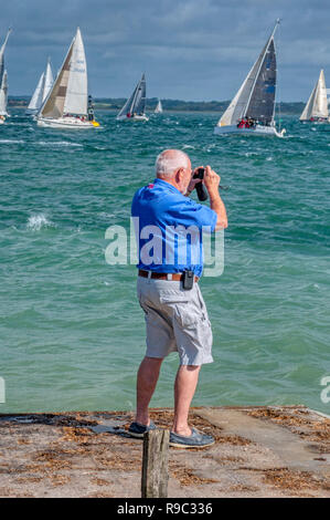 Alter Mann betrachten und Fotografieren von Yachten, die Solent, Isle of Wight, Großbritannien Stockfoto