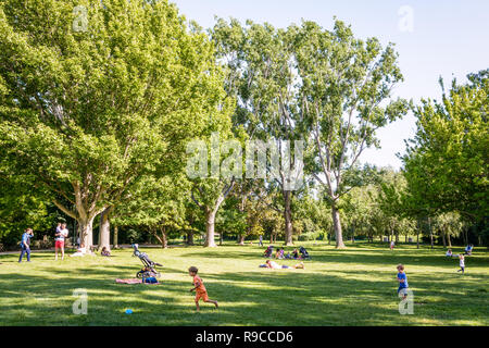 Kinder spielen Ball, Familien in den Schatten und Menschen beim Sonnenbaden auf dem Rasen im Borely Park in Marseille, Frankreich am Ende eines sonnigen Tages ausruhen. Stockfoto