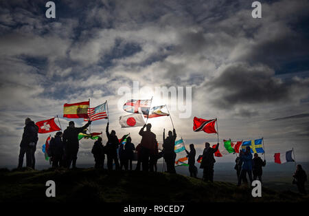 Bewohner von Lockerbie und andere durch die Bombardierung klettern Burnswark Hill betroffen, oberhalb der Stadt Lockerbie, in Dumfries und Galloway mit 21 Fahnen, Vertreter der 21 Nationalitäten der Opfer, für die für den Frieden bei den 30. Jahrestag der Flugzeugkatastrophe zu gedenken. Stockfoto