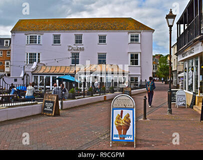 Die Menschen genießen einen entspannenden Drink in der offenen vor Dukes Hotel mit Blick auf die Esplanade und dem Meer, im traditionellen Badeort Sidmouth. Stockfoto