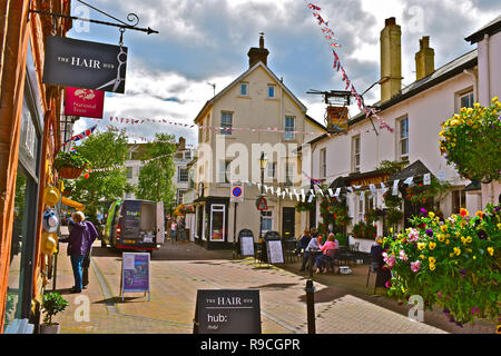 Das Stadtzentrum von Sidmouth mit bunten Wimpelketten, hängende Körbe und schattigen Bäumen. Die Menschen genießen einen entspannenden Drink außerhalb der Anchor Inn Pub. Stockfoto