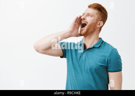 Taille-up Shot sorglosen gewöhnlichen stattlichen redhead reifer Kerl in Grün Polo, links Holding palm in der Nähe von geöffneten Mund, Kopf, während laut schreien, Freund kommen zum Abendessen Stockfoto