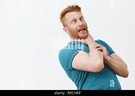 Es ist mir lachen. Portrait von lustigen sorglos und verspielten rothaarige Kerl mit Borsten, biegen nach hinten, während er sich an den Hals halten, Würgen für Spaß, die Zunge und das Schielen Stockfoto