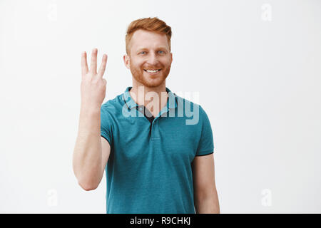 Cute kaukasischen freundlich rothaarige Mann bestellen drei Schüsse von Barkeeper, lächelte breit Anzahl Dritter und breit grinsend, entspannen in der Kneipe mit Freunden über grauer Hintergrund Stockfoto